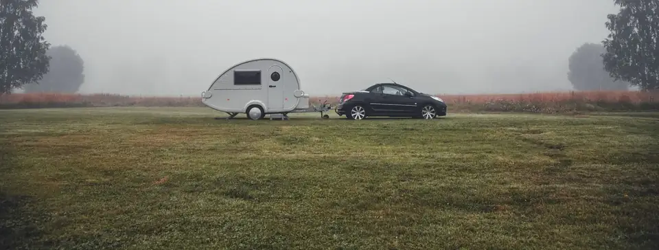 Auto met caravan op een weiland in de mist